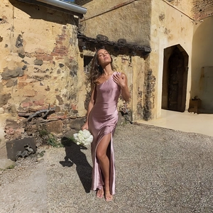 Detail of elegant pink satin one-shoulder dress with high slit in vintage courtyard