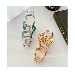 Elegant gold and silver snake-shaped metal hair claws with hollowed design on white surface