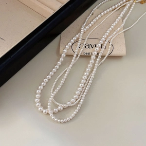 Elegant layered pearl necklace with multiple strands and gold clasp on blue velvet box
