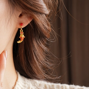 Détail d'une boucle d'oreille carpe koi dorée avec perle rouge sur un mannequin
