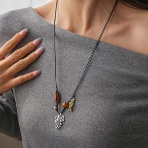 Gros plan du collier pendentif raisin en argent avec perles en bois et cordon noir