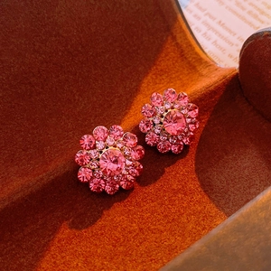 Macro shot of pink floral crystal earrings with gold base on dark velvet background