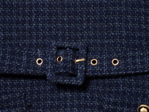 Détail de robe en tweed bleu marine avec tissu texturé et œillets en métal doré chic