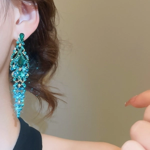 Macro view of long vintage gold drop earrings with turquoise stones on a female model