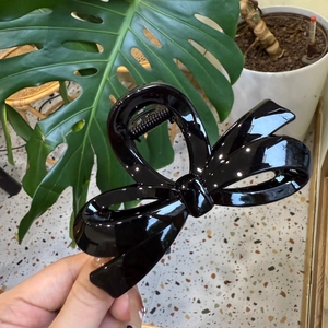 Detail of a large black glossy bow hair claw clip showing the irregular spring structure