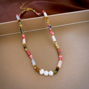 Detail of baroque pearl and gemstone necklace on luxury satin and golden tray