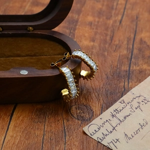 Detail of C-shaped gold-plated hoop earrings with micro-paved cubic zirconia stones
