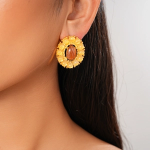 Macro shot of oval reddish-brown gemstone earring with yellow stones in gold setting