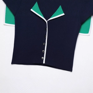 Navy blue knitted top with green contrast collar and silver buttons on white background