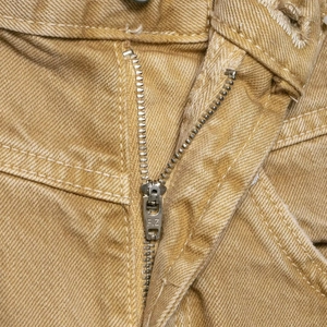 Detail der khakifarbenen Low-Rise Jeans mit Metallreißverschluss und diagonalem Twillstoff
