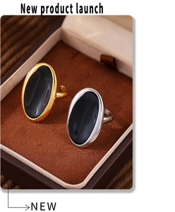 Close-up of gold and silver adjustable rings with oval black enamel on velvet lining