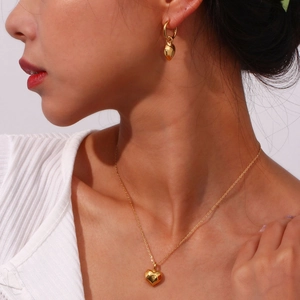 Elegant gold heart pendant necklace and earring set shown on model for a chic look