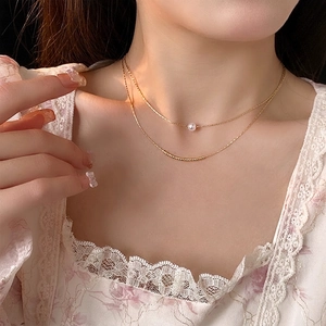 Elegant double layer gold necklace featuring a baroque pearl and metallic bar pendant