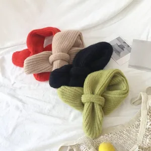 Detailed flat lay of soft knitted baby scarves in red, beige, black, and green colors