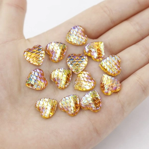 Close-up of heart-shaped gold fish scale resin charms for DIY jewelry making