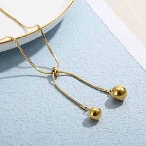 Detail of adjustable gold bead slider on snake chain necklace with metallic sphere charms