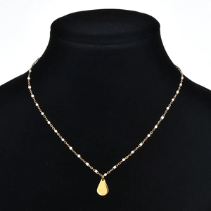 Detail of gold beaded necklace with drop pendant on a black bust mannequin display