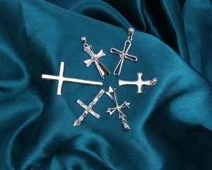 Gros plan de divers pendentifs en forme de croix s925 sur tissu satin vert