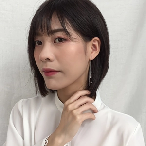 Detail of silver long tassel earrings with moon star design worn by model on white background