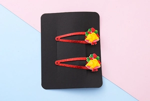 Detail of Christmas glitter BB clips with yellow resin bells and festive red bows