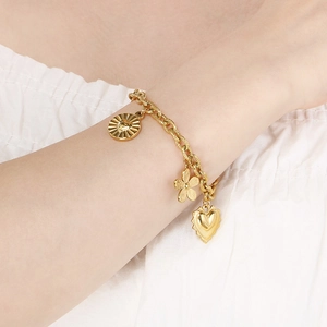 Bohemian gold stainless steel bracelet with heart and flower charms on a model wrist