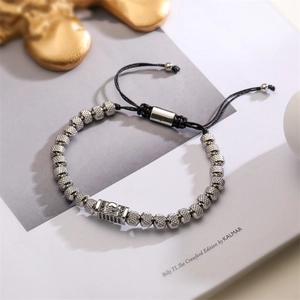 Detail of silver skull pendant with black gems on an adjustable braided bead bracelet