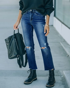 Gedetailleerd beeld van donkerblauwe ripped jeans met distressed knie en rechte pijpen