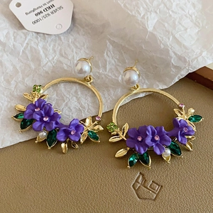 Detail of vintage gold butterfly hoop earrings with purple flowers and green rhinestones