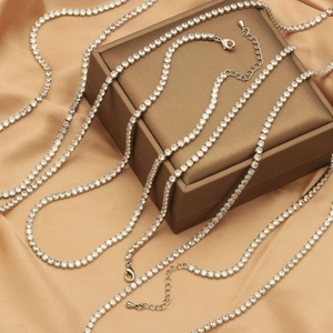 Detail of silver tennis necklaces with clear zircons on brown jewelry box and silk