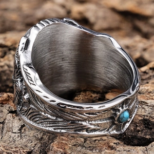 Vintage eagle feather engraved steel ring with turquoise stone inlay on bark background