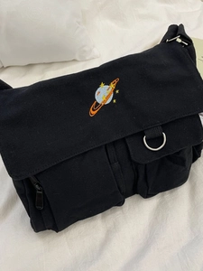 Minimalist black canvas messenger bag with saturn embroidery and multiple pockets