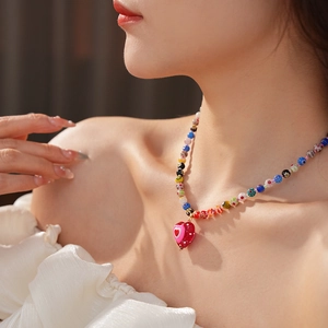 Detail of colorful glass beaded necklace featuring a large red heart-shaped pendant on a model