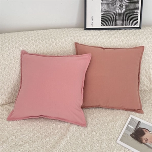 Minimalist square solid color pillowcases in pink and red on a white fleece sofa