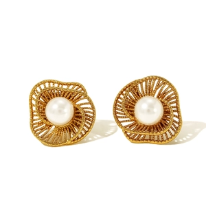 Détail de boucles d'oreilles dorées avec perle centrale blanche et design texturé rayon
