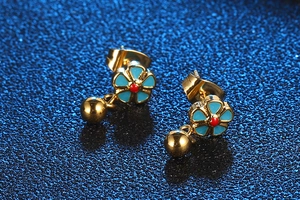 Macro view of floral titanium steel earrings with blue petals and a hanging gold bead