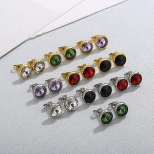 Détail de boucles d'oreilles clous ronds en cristal coloré et montures dorées