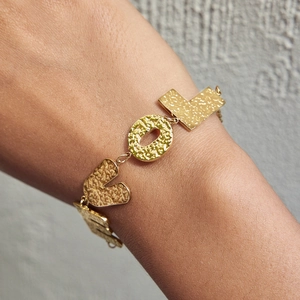Macro shot of gold hammered metal LOVE charms on a classic stainless steel chain