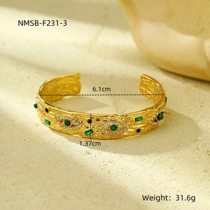 Macro detail of gold evil eye bangle with green gemstone and white crystal inlay