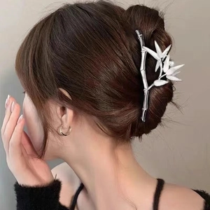 Close-up of bamboo-shaped silver hair claw with white leaves and pearl on hair