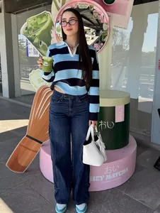 Detail of blue and black striped polo knit sweater with high-waist wide-leg denim jeans