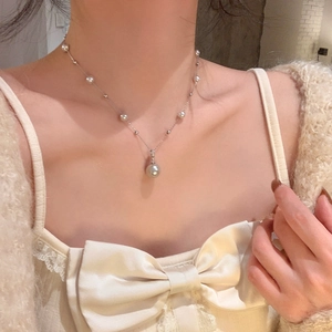 Detailed close-up of a silver tassel necklace with elegant pearls on a model neck