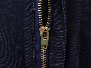 Dettaglio di una cerniera in ottone di alta qualità su denim blu scuro con cuciture fini