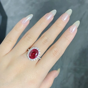 Close-up of an oval red ruby ring with sparkling diamond halo on silver band