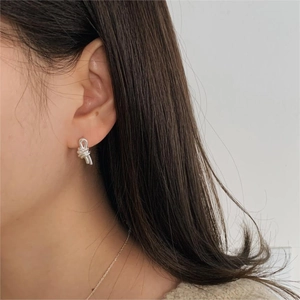 Close-up of minimalist silver knot stud earring worn by model in a clean lifestyle shot