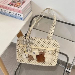 Detail of beige polka dot ita bag with transparent PVC layer and plush bear decorations