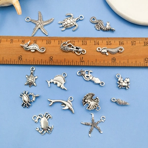 Collection of 15 silver ocean charms like turtles and seahorses shown with a wooden ruler