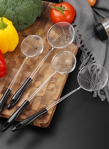 Macro detail of stainless steel strainers with black ergonomic handles on a wooden board