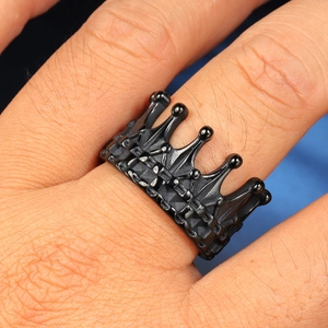 Close-up of a matte black crown-shaped titanium steel ring worn on a person's finger