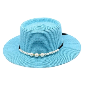 Dettaglio di un cappello di paglia blu con eleganti decorazioni in perle e nastro nero