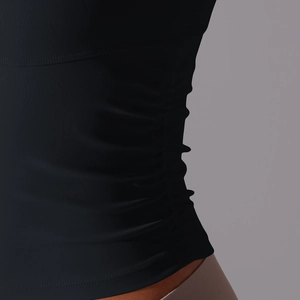 Gros plan sur les détails froncés latéraux de ce débardeur de yoga noir et respirant